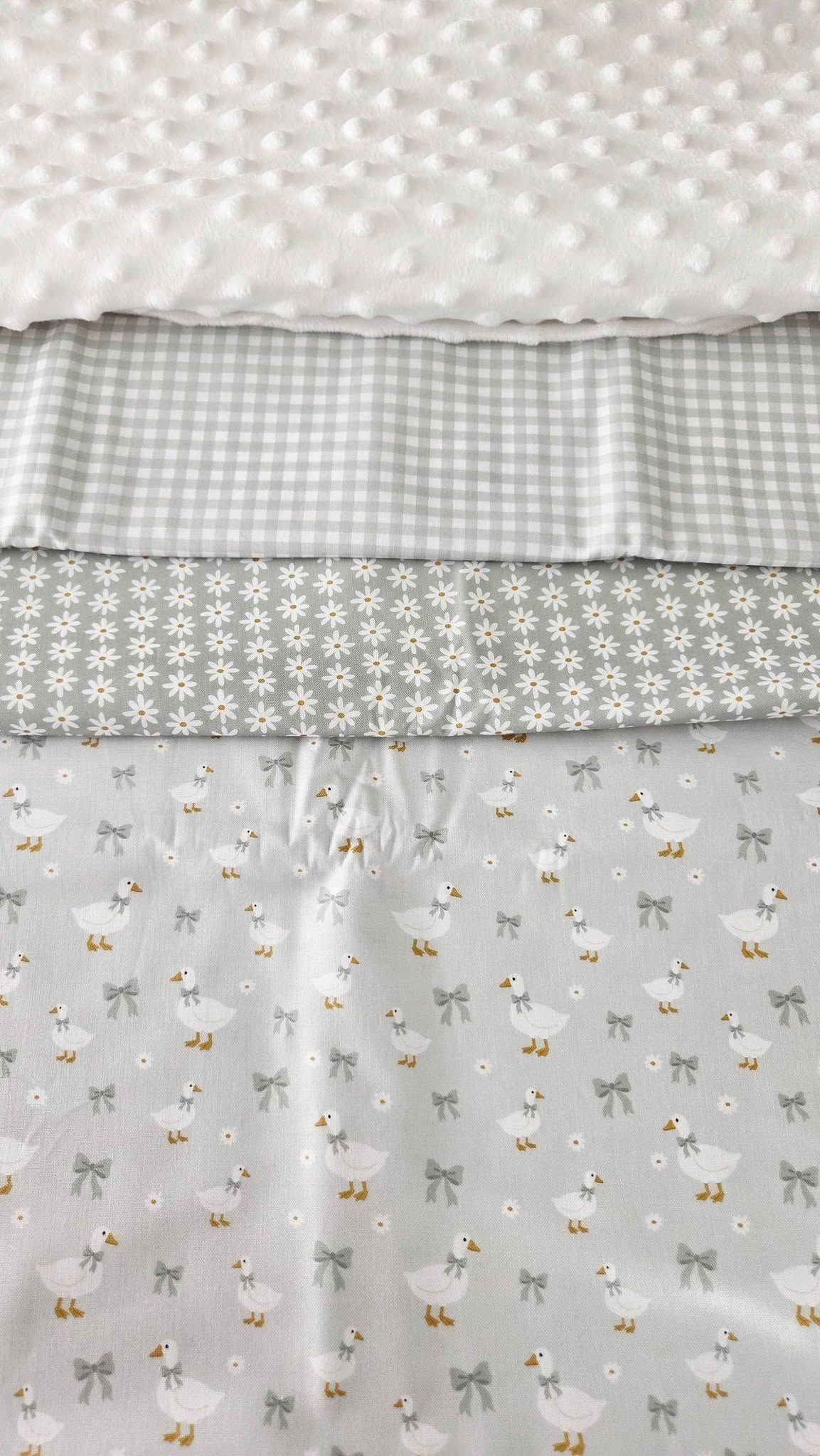 Gray and white baby fabric bundle featuring gingham, daisy, and goose with bow prints alongside white minky dot fabric.