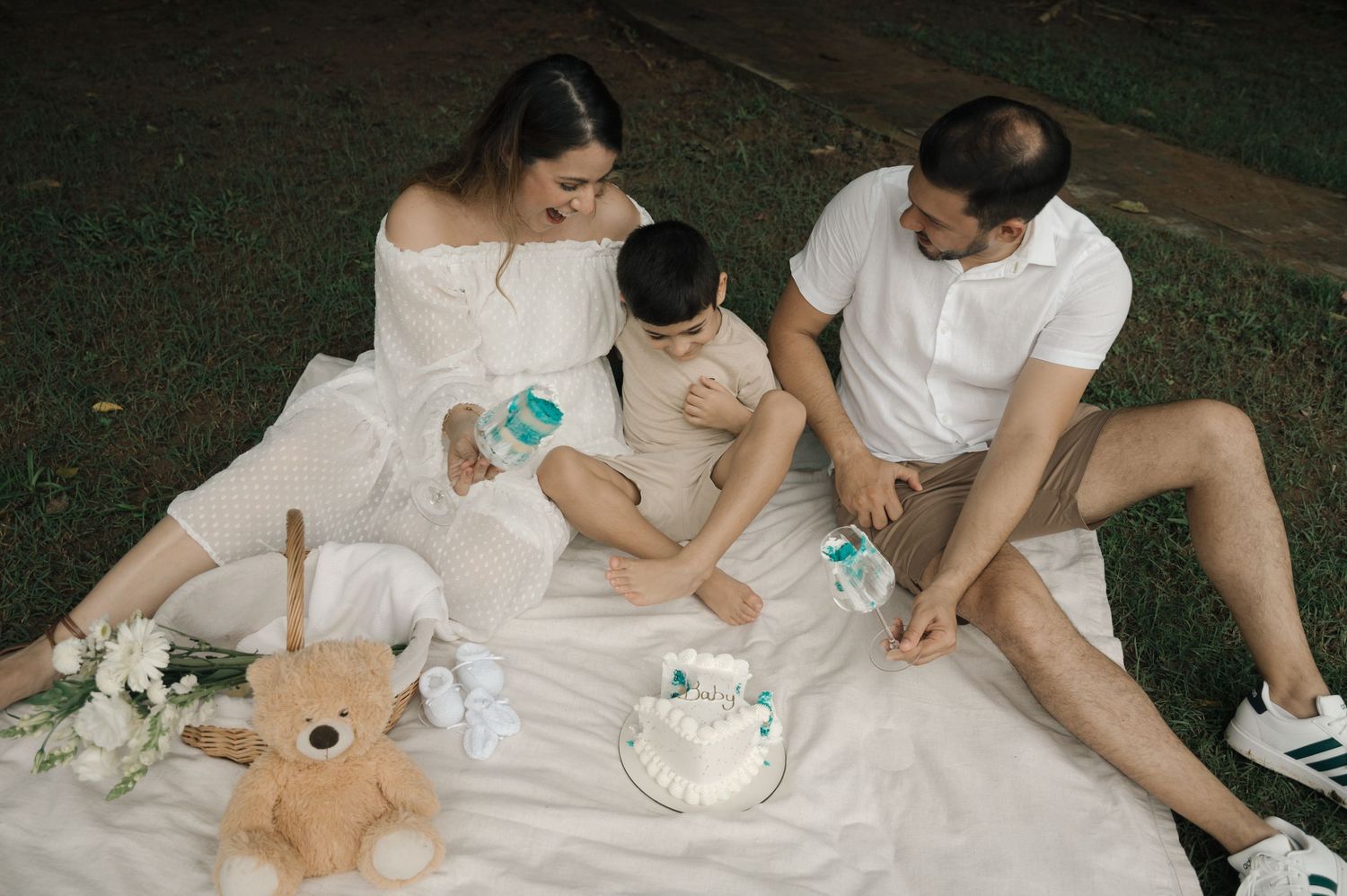 Happy family moment captured at outdoor party with dessert table and red flowering background.
