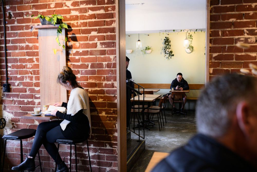 Cafe interior with exposed brick walls and customers sitting at tables.