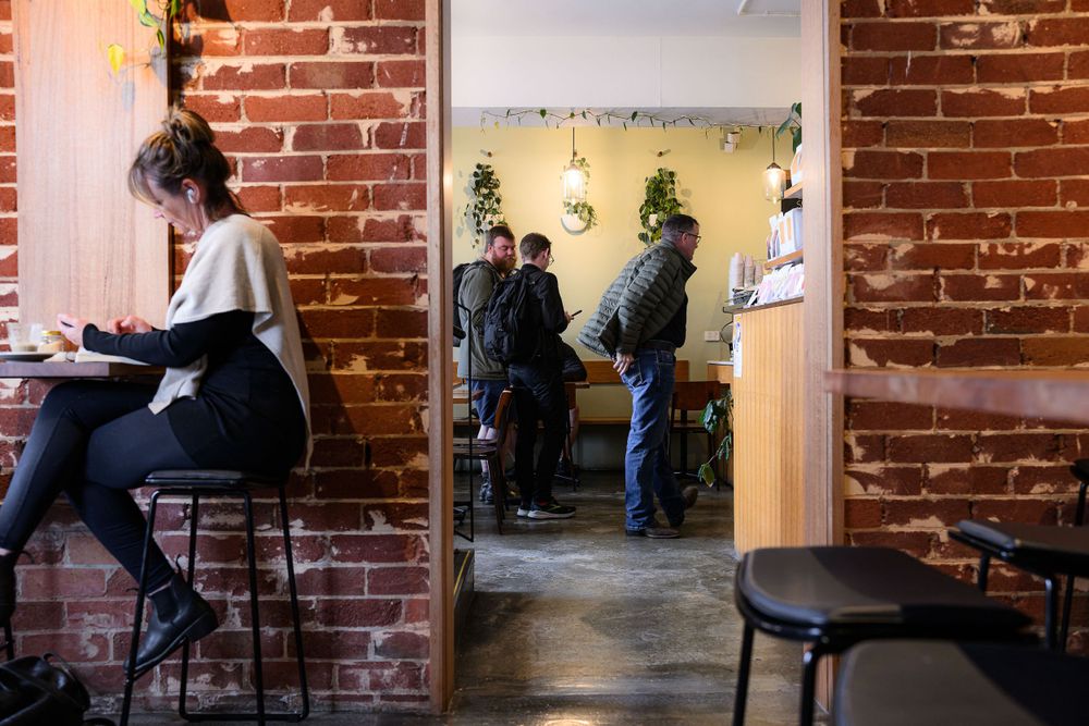 Coffee shop interior with exposed brick walls and customers seated at counters.