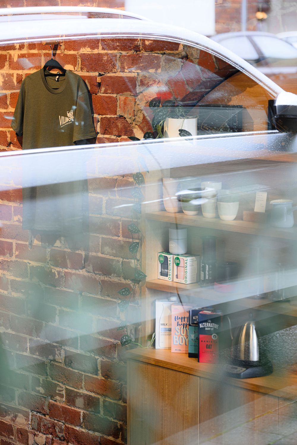 Interior view of a coffee shop with exposed brick walls and retail shelves displaying products.