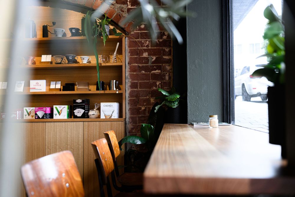Cozy cafe interior with wooden shelves, exposed brick wall, and natural lighting.