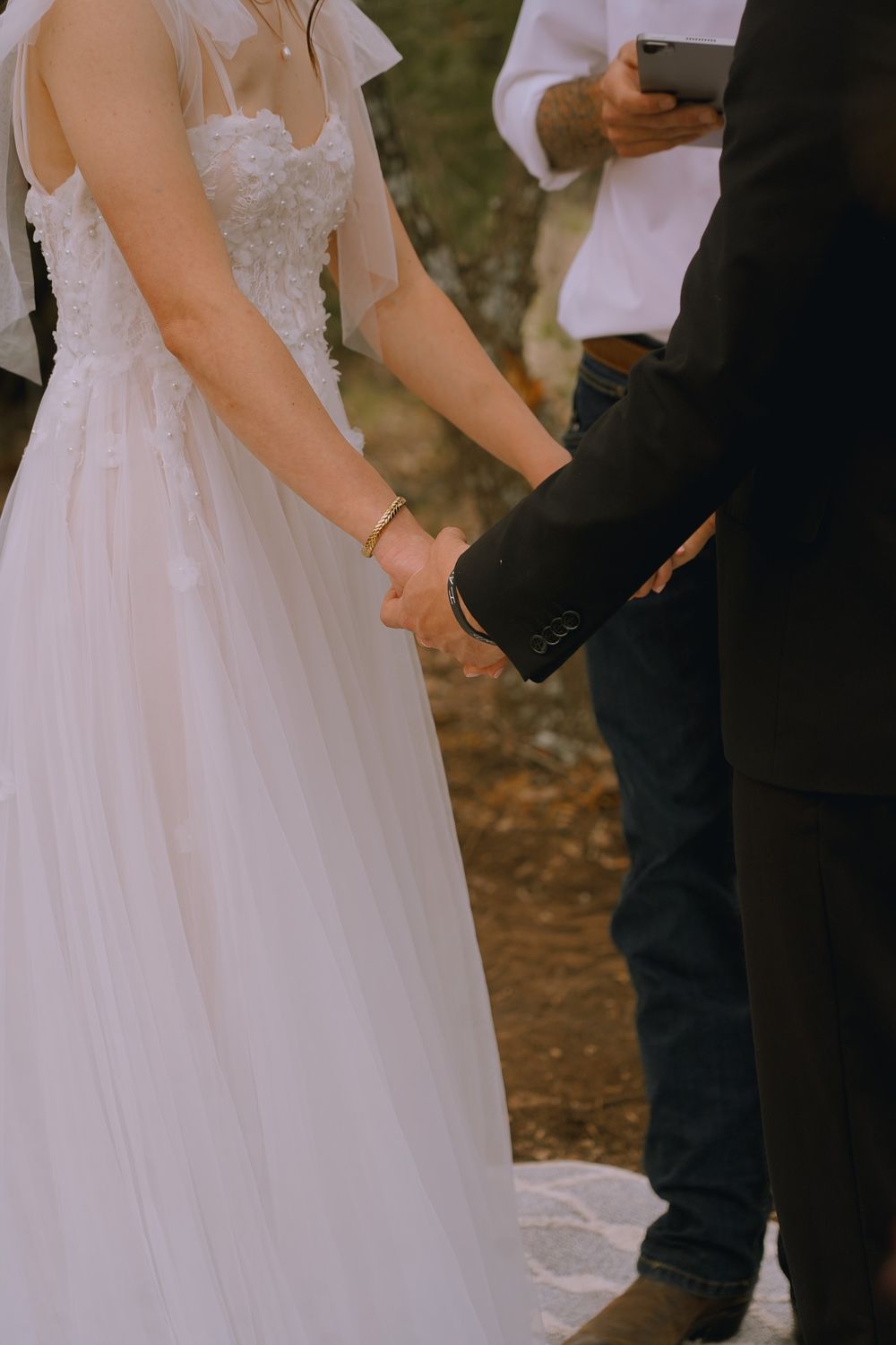 Close-up of bride and groom holding hands during wedding ceremony.