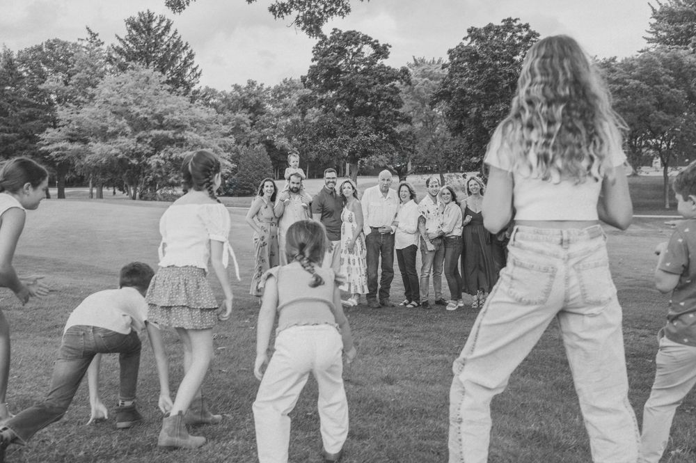 Students gather on a grassy outdoor field during what appears to be a group activity or class at a school or campus.