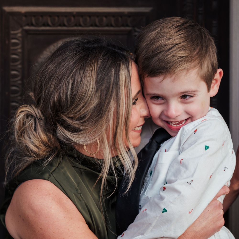 A tender moment of joy and laughter between a parent and child, sharing an intimate embrace against a dark background.