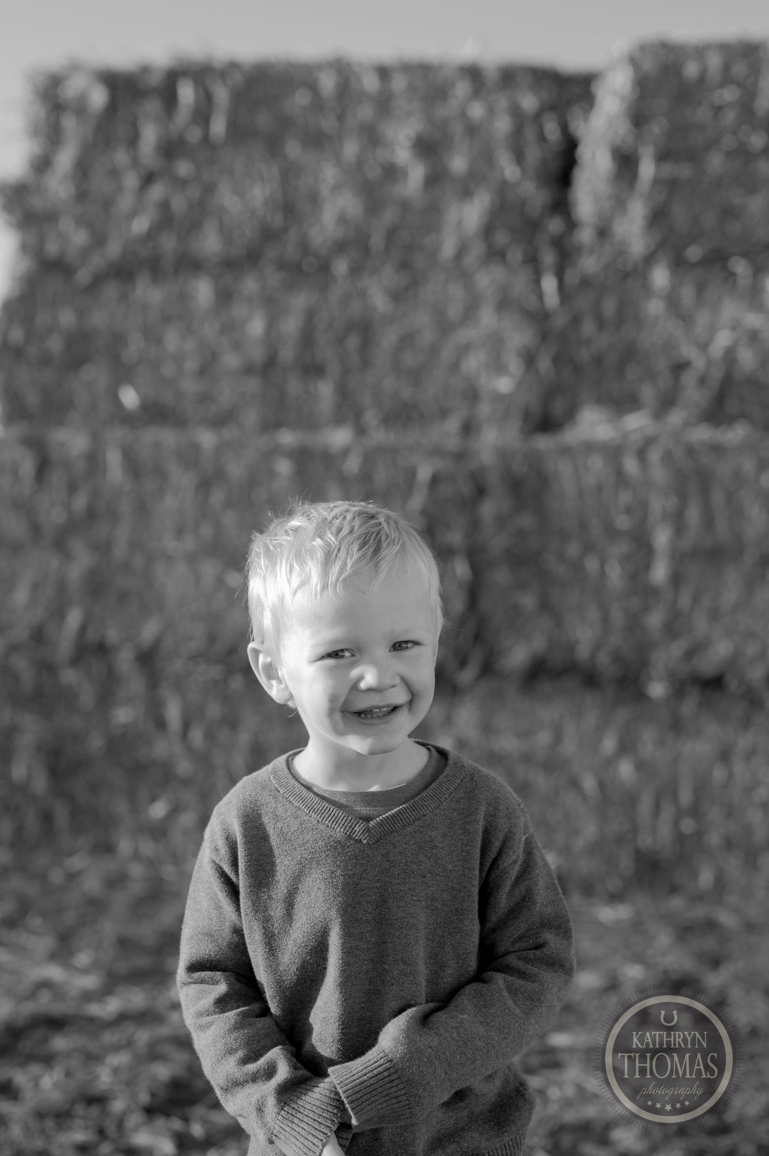 A black and white portrait of a young child against a textured wall background.