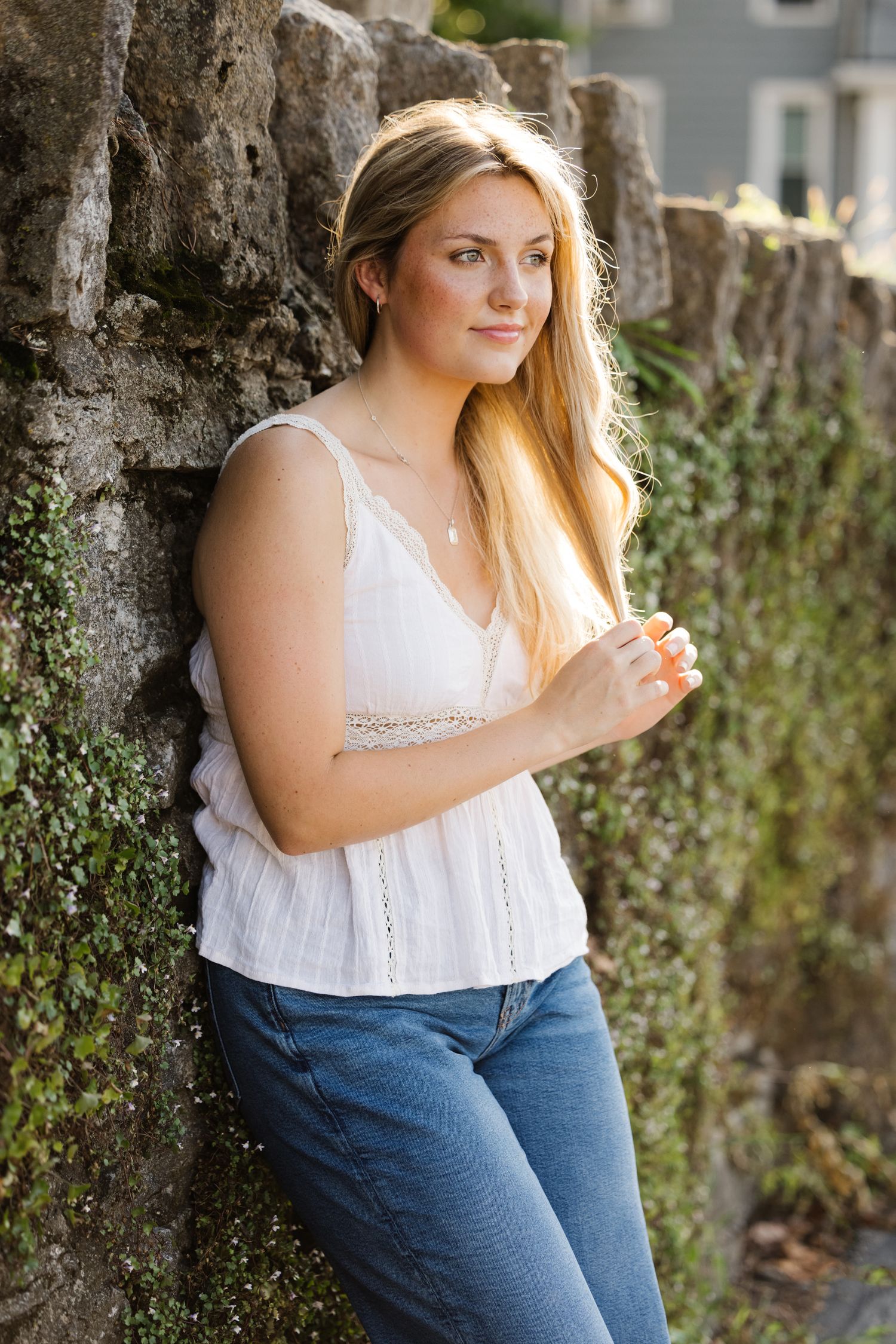 Natural outdoor portrait against textured stone wall with green foliage.