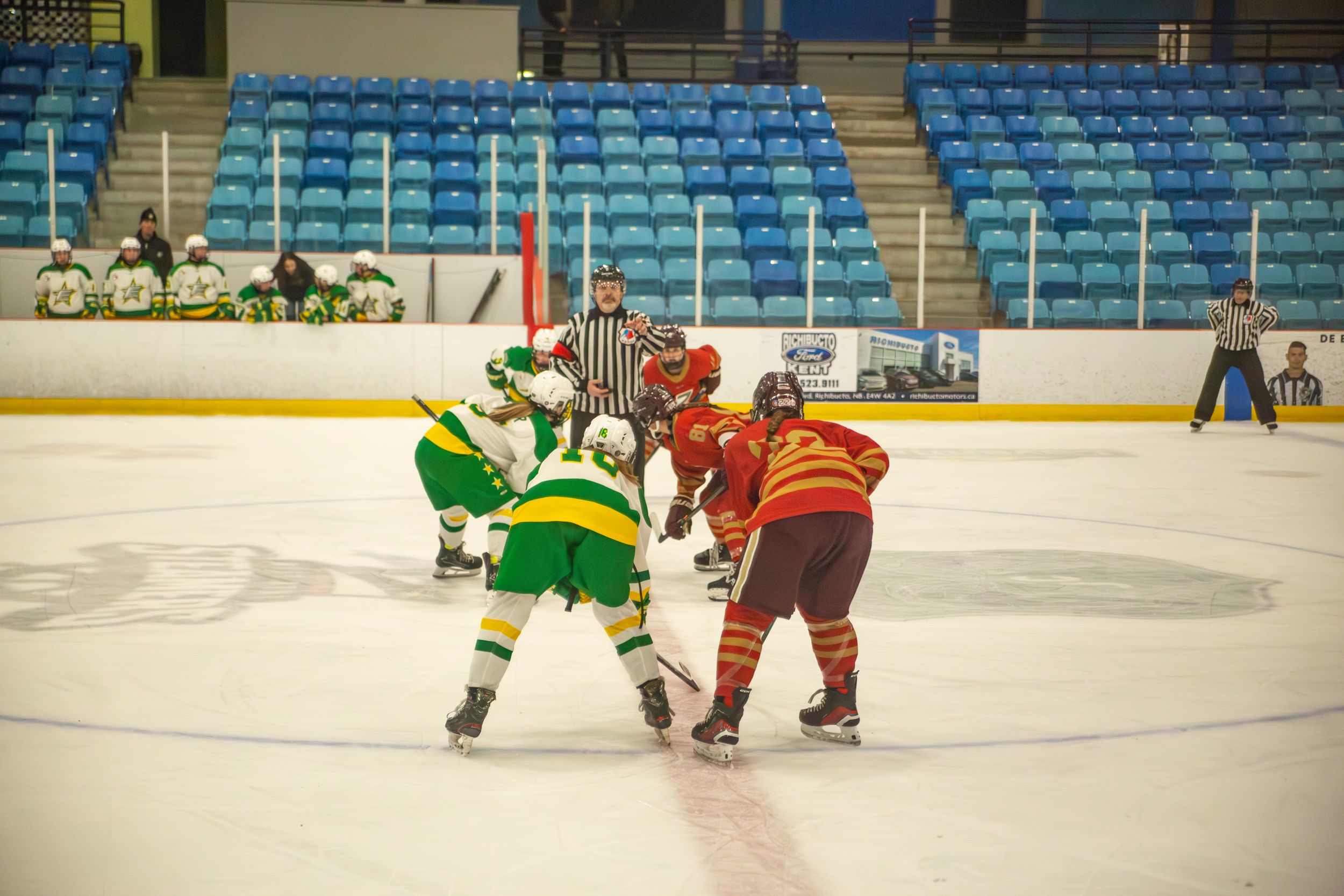 Hockey players from opposing teams prepare for face off at center ice.
