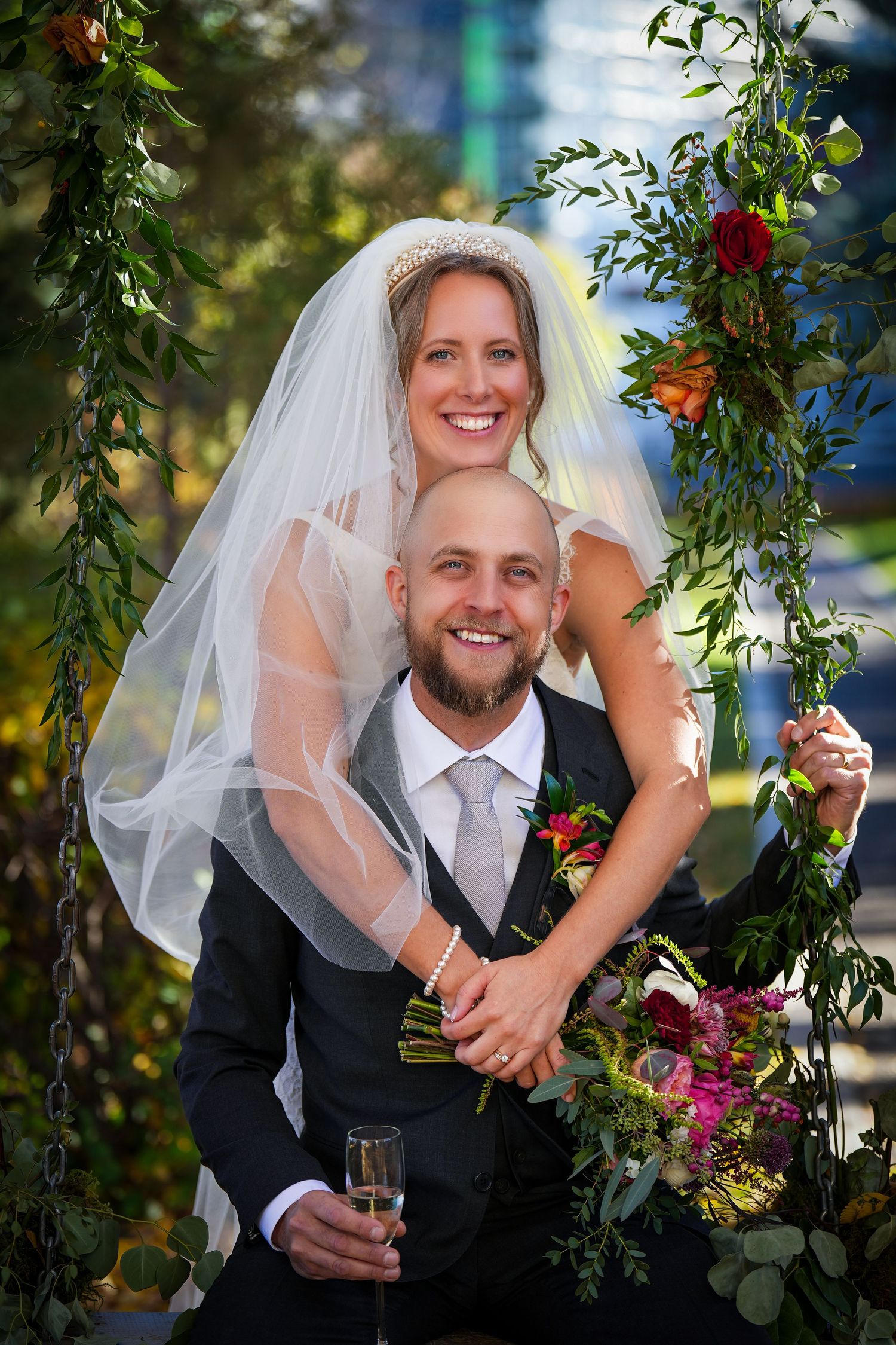 Newlyweds sharing a joyful moment on a floral-decorated swing at their outdoor wedding.