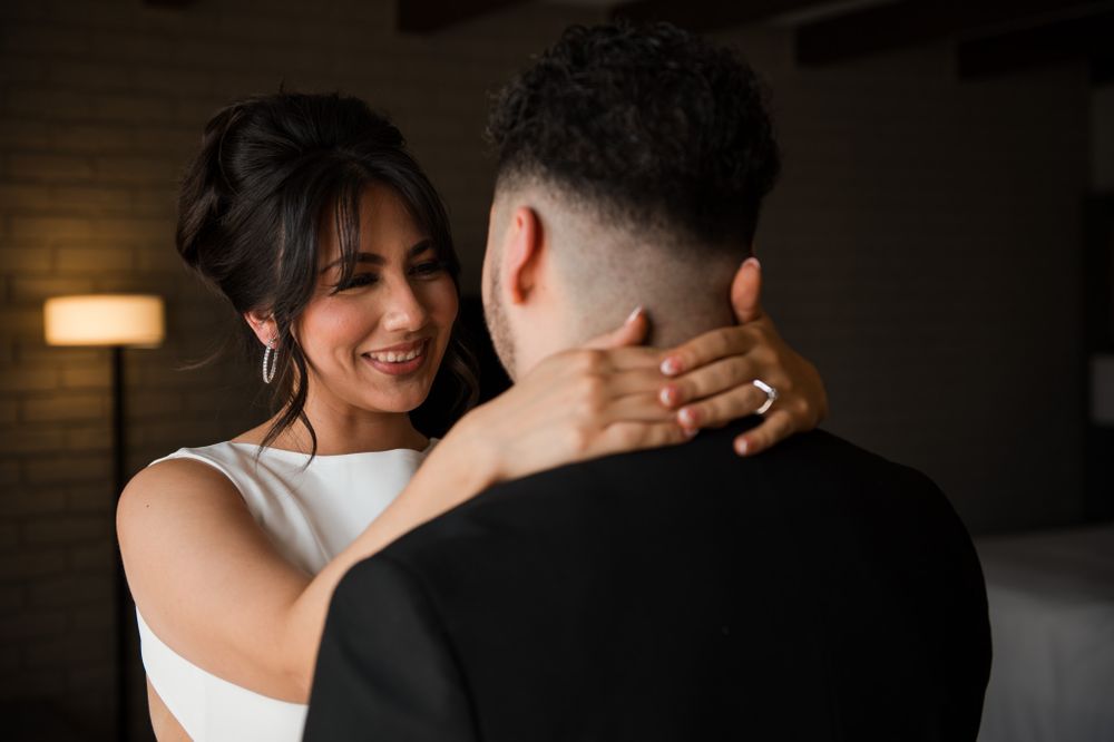 Intimate wedding moment of couple embracing in dimly lit room.