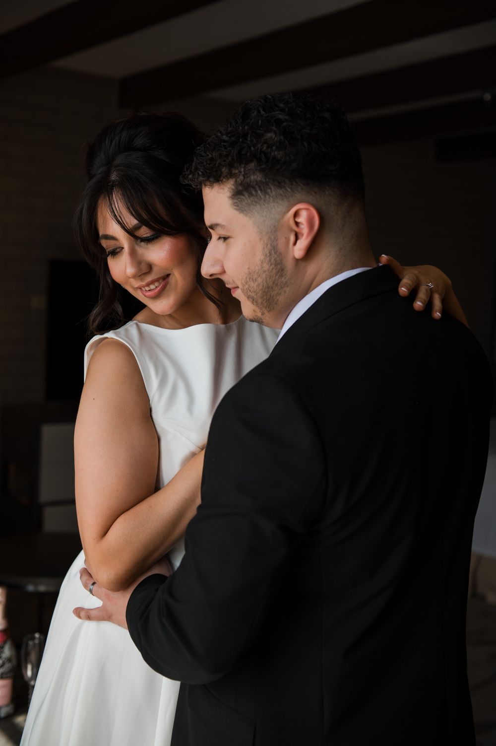Couple sharing tender moment in formal wedding attire indoors.