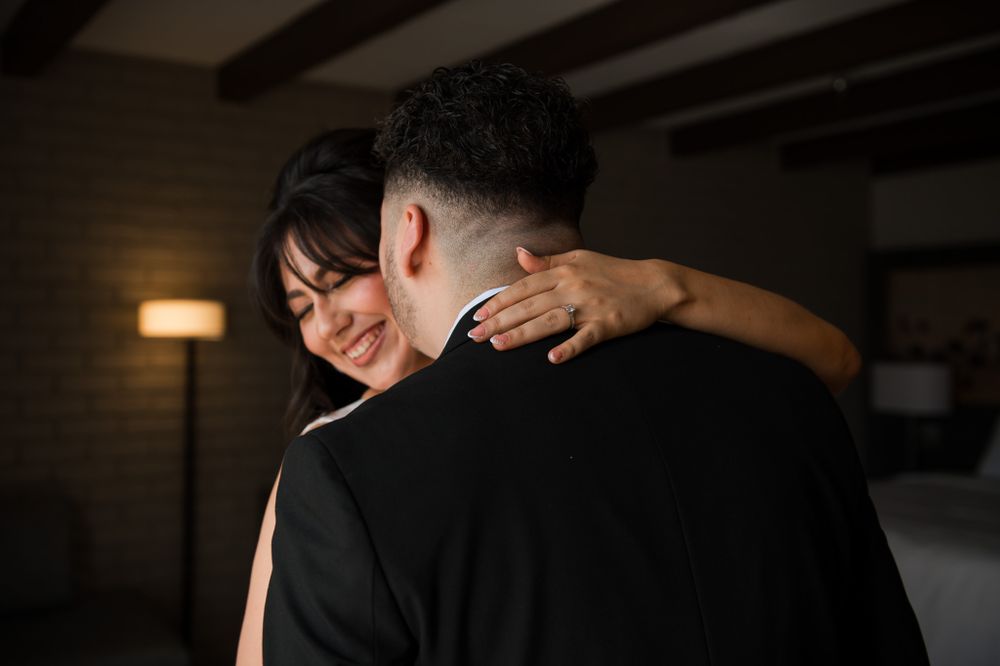 Romantic embrace between couple in wedding attire with warm lighting.
