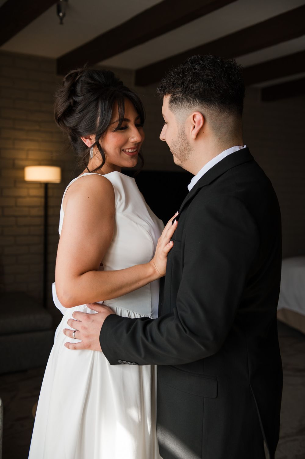 A romantic wedding couple embraces in a candid moment, with the bride in white and groom in black.