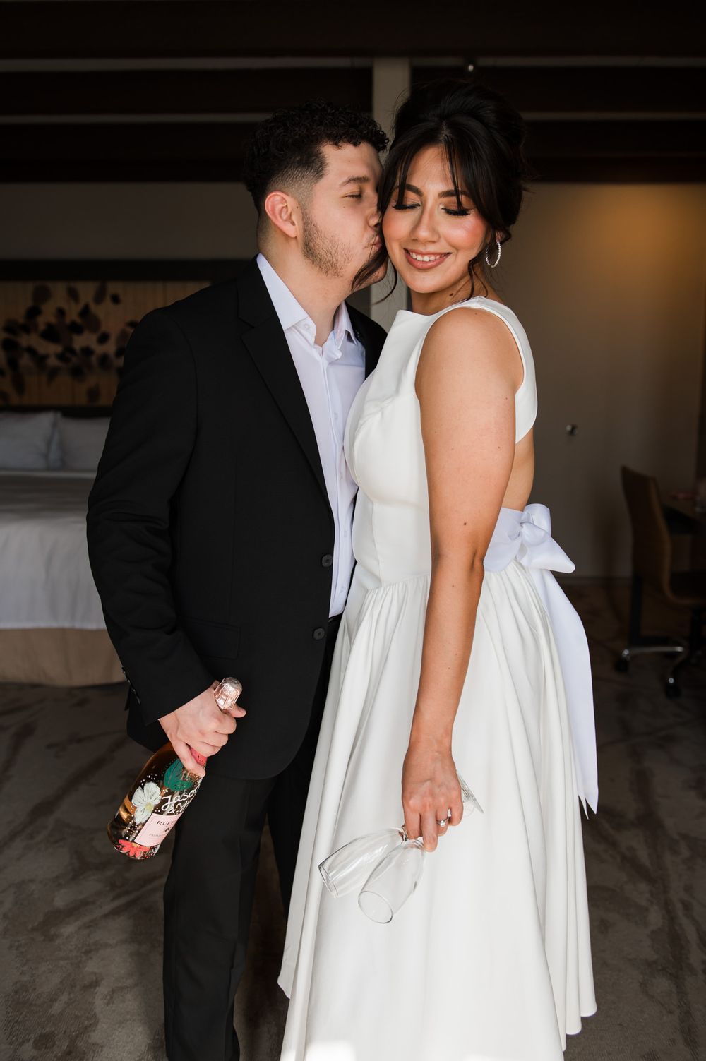 Elegant wedding couple shares playful moment in formal attire during reception.