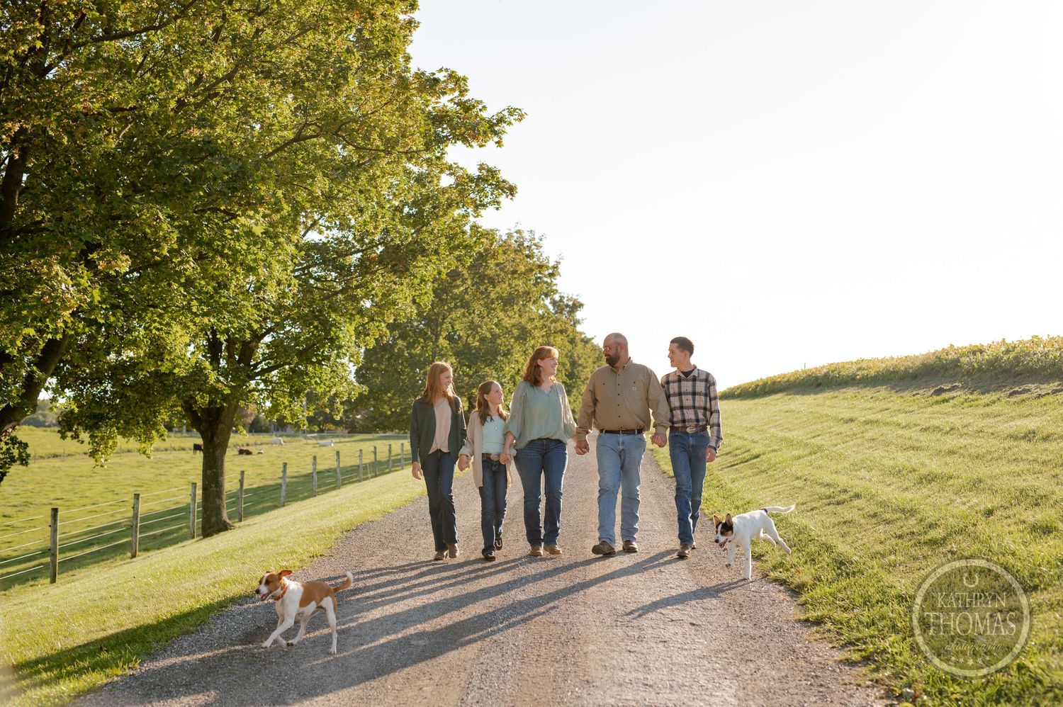Family walks together with their dog on a country path during golden hour.