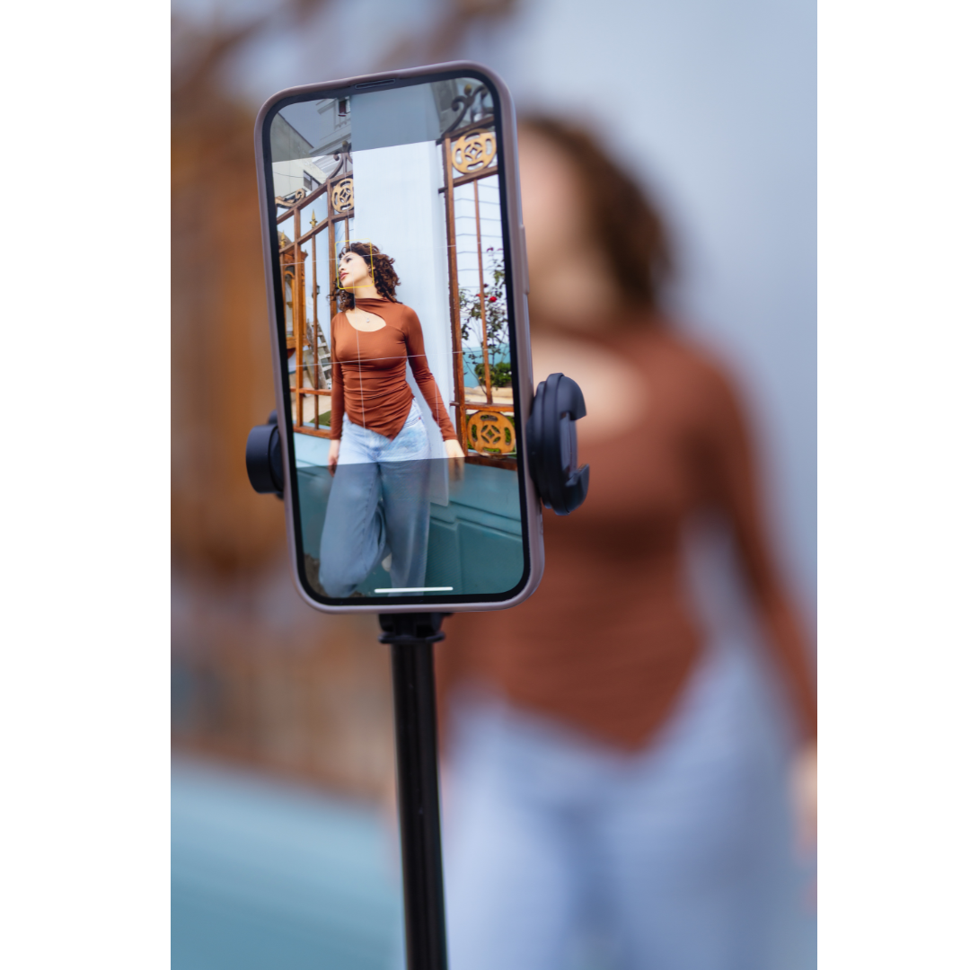 Phone mounted on stand capturing a fitness scene through its screen in a gym setting.