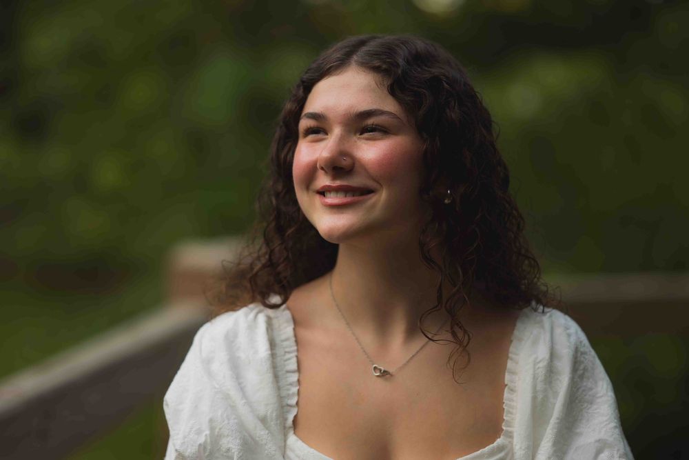 Smiling person in white lace outfit poses outdoors against greenery in a series of candid shots.