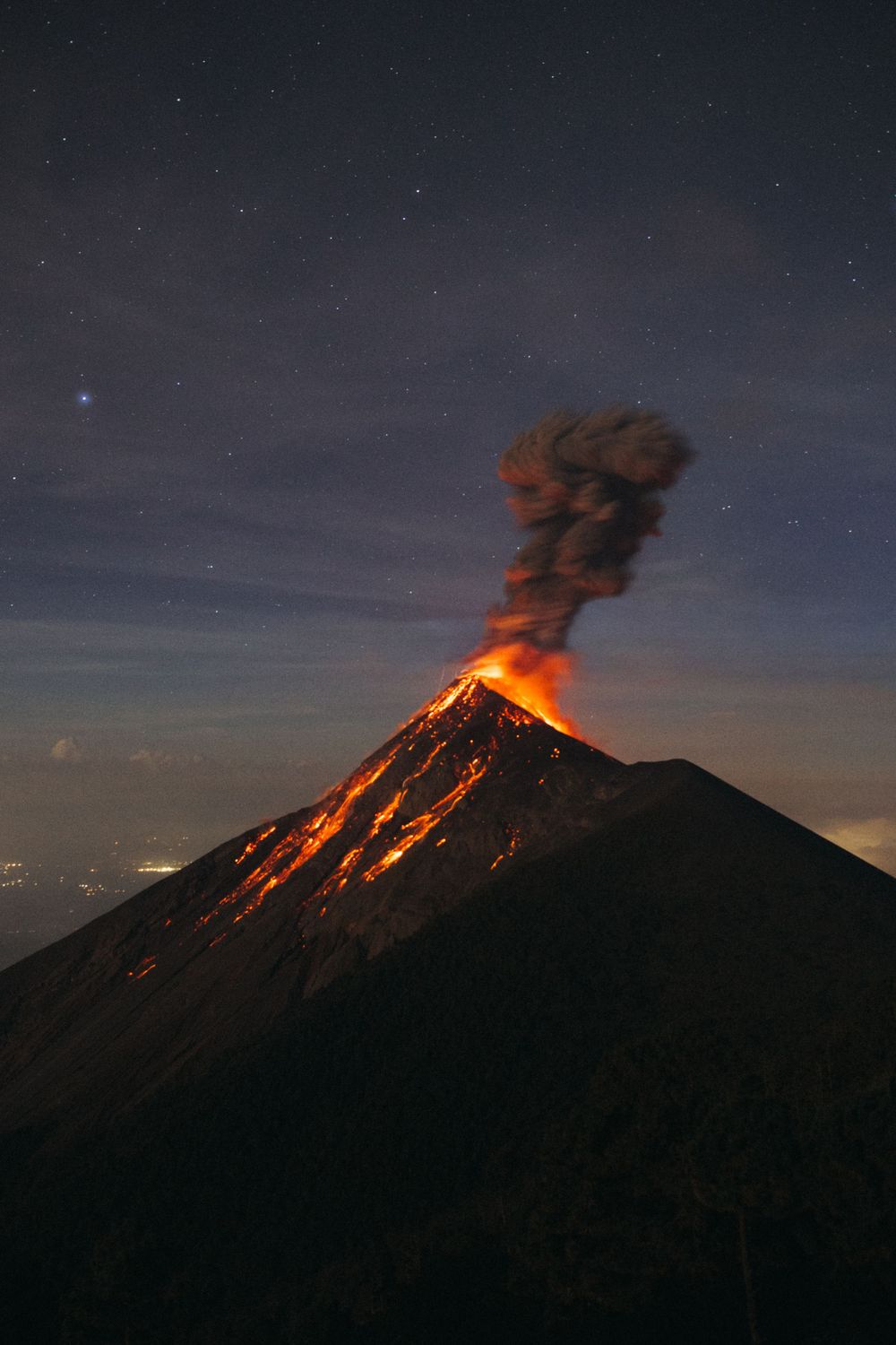 Time-lapse sequence of Mount Merapi volcano erupting at night with glowing lava and ash plumes against starry sky.