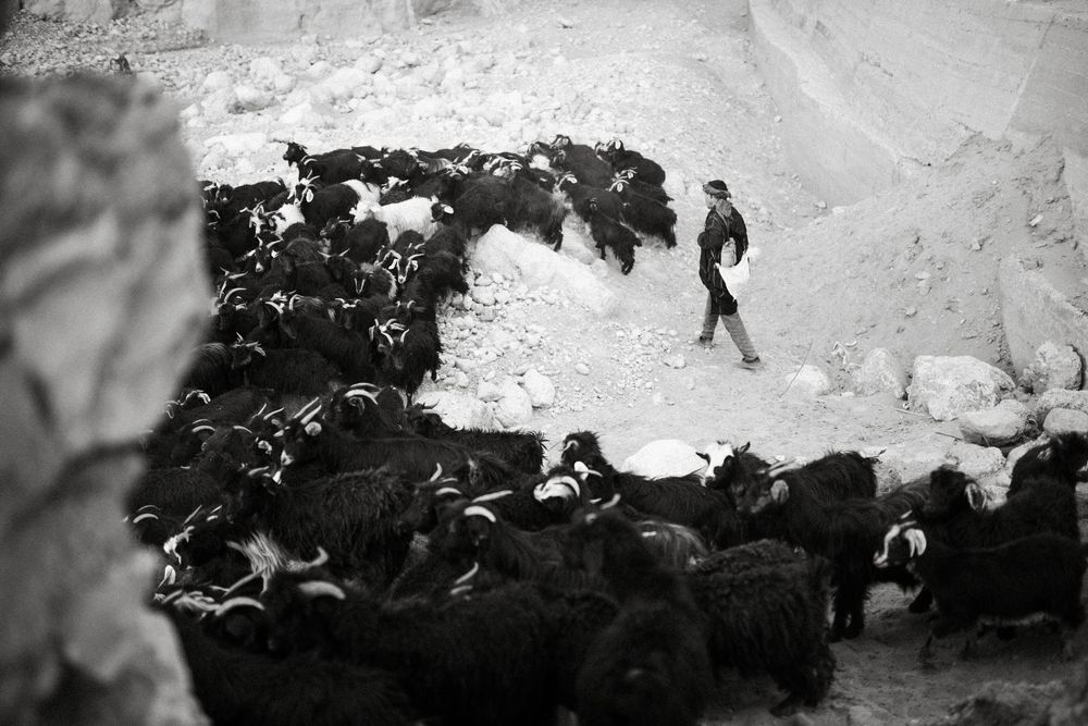 Vintage black and white photograph showing a dramatic mountainous winter landscape with figures in the distance.