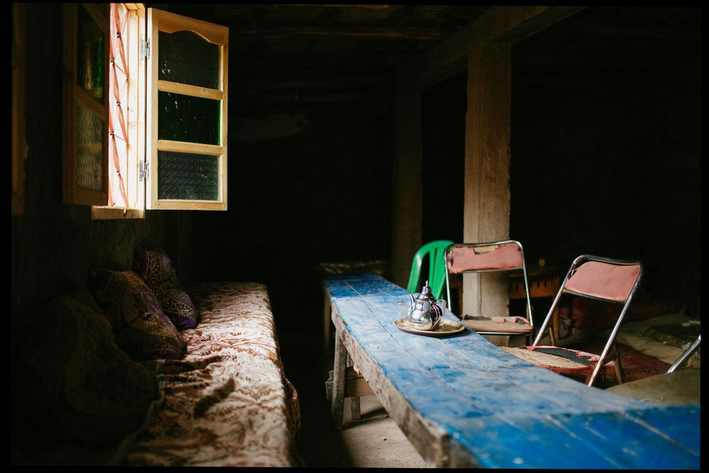 Light streams through a small window in a dark, rustic wooden cabin interior with a ladder visible.