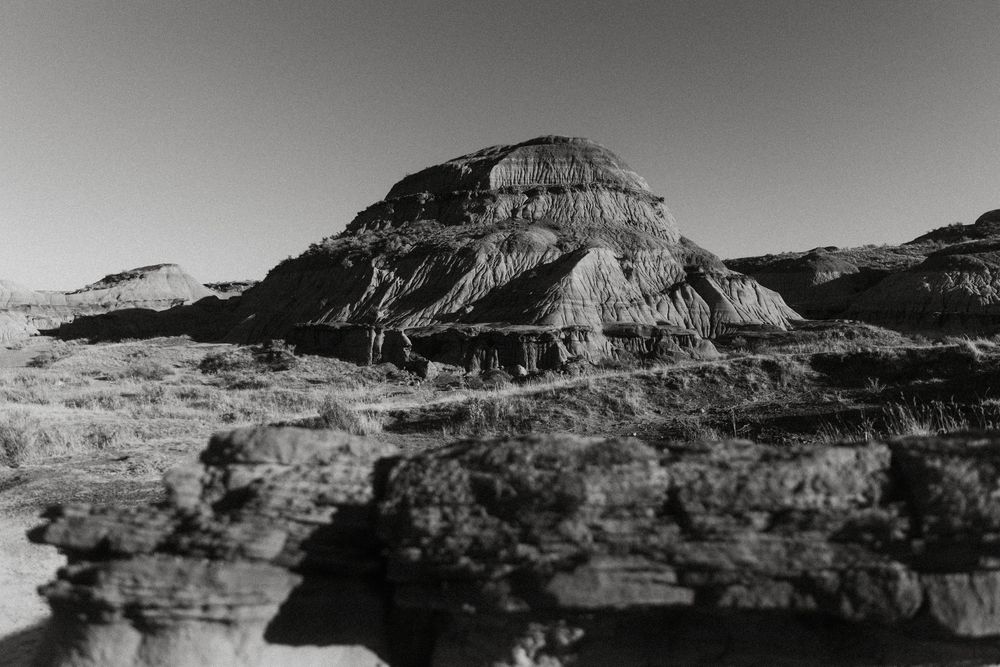 Panoramic black and white landscape photograph showing eroded rock formations in a desert canyon setting.