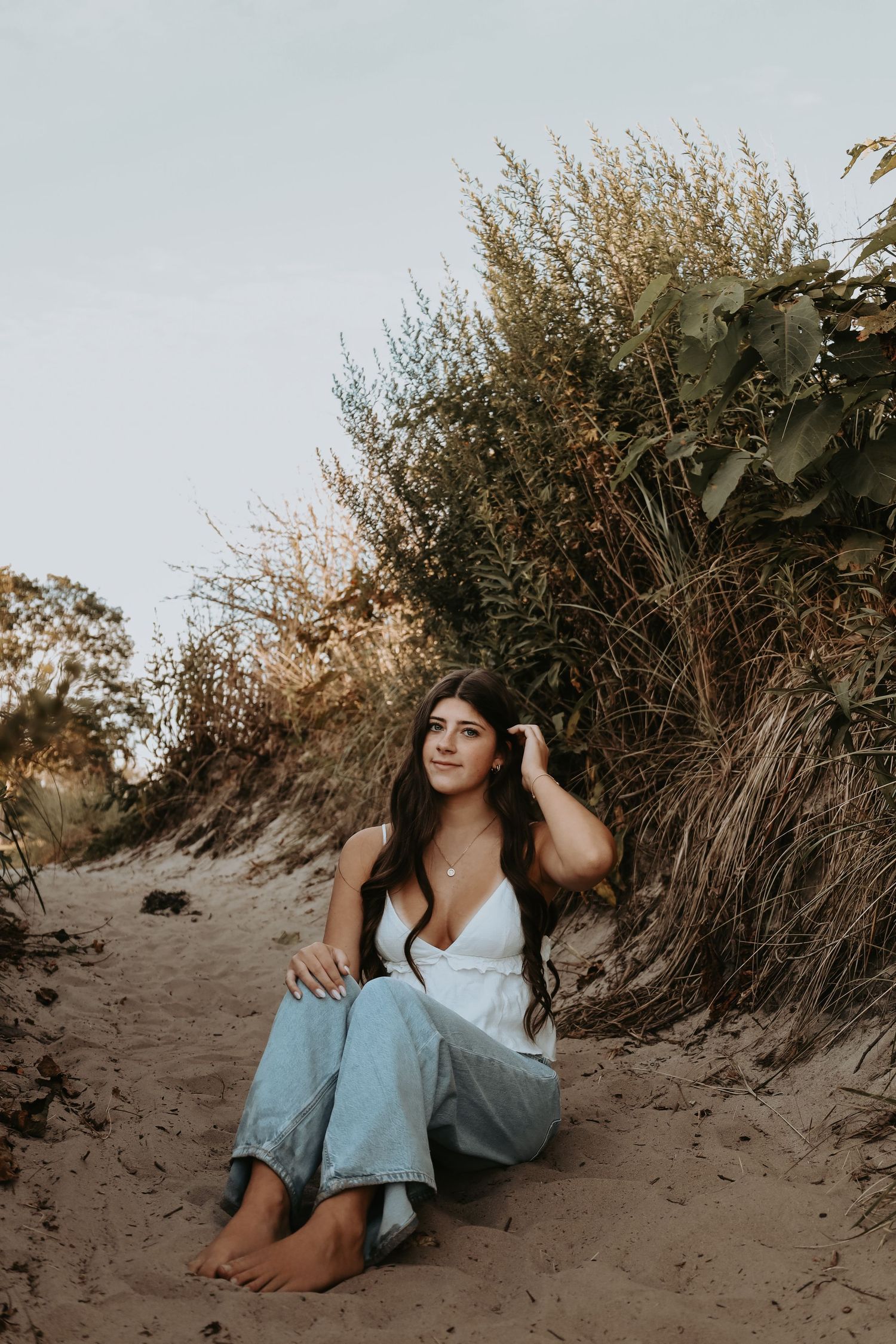 A series of artistic beach portraits showing someone reclining on sand dunes at sunset with natural vegetation.