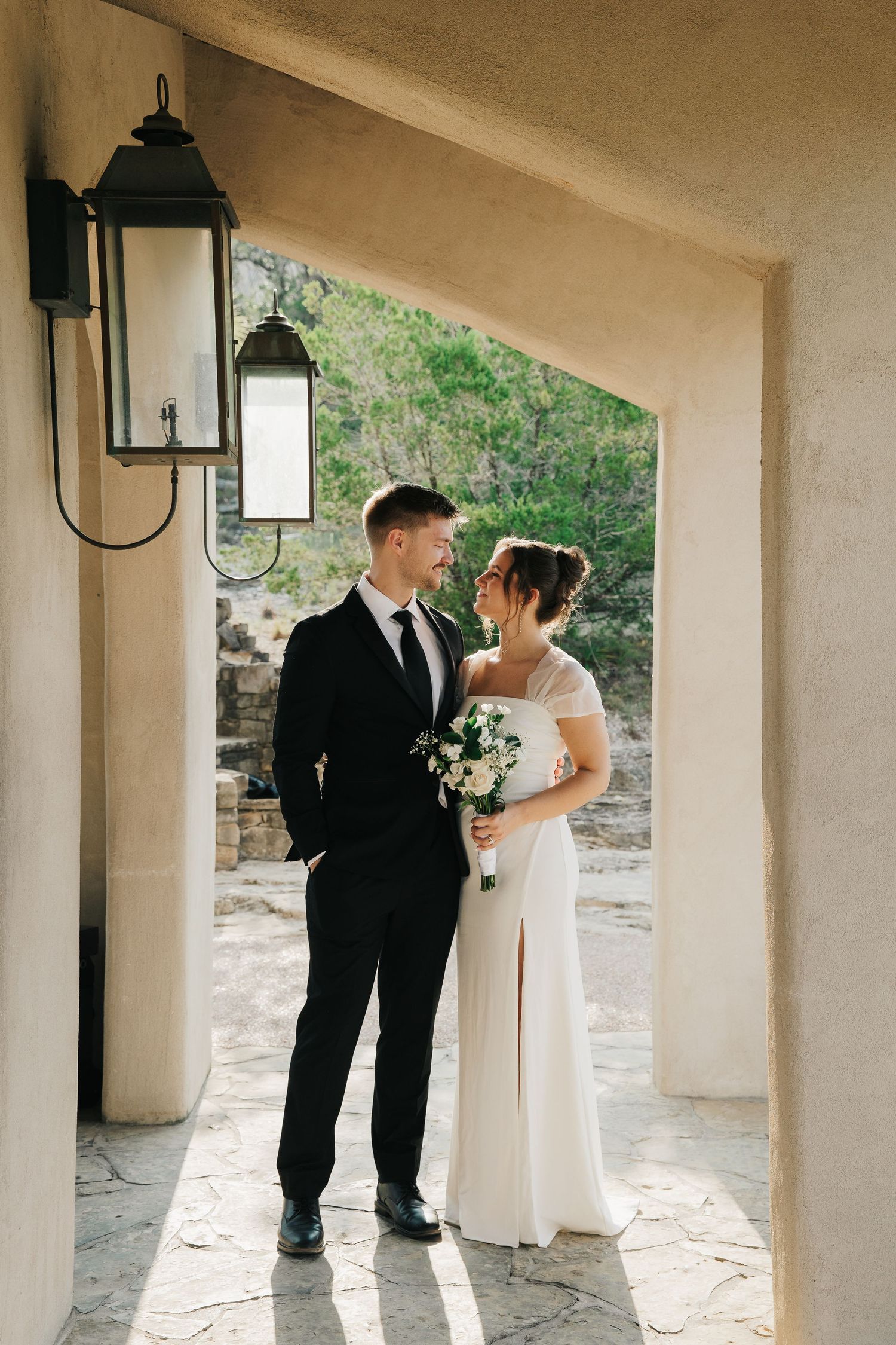 A floral dress and white veil hanging on a tree branch along a garden path.