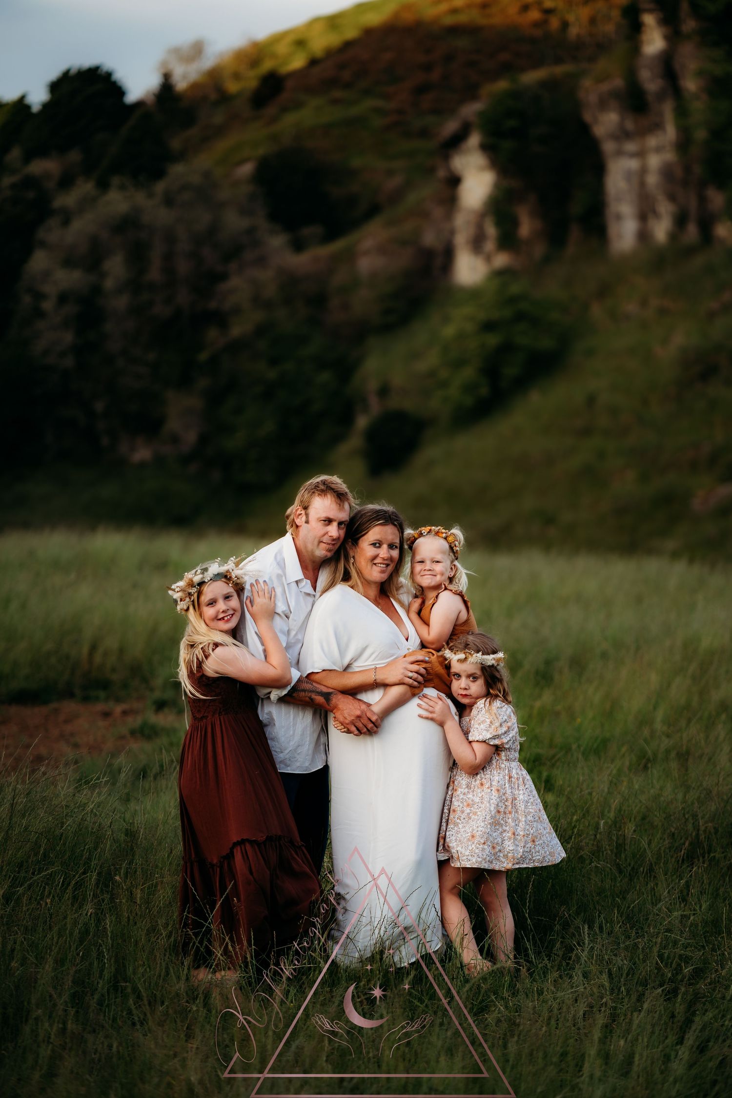 Family group portrait in front of dramatic cliffs at golden hour.
