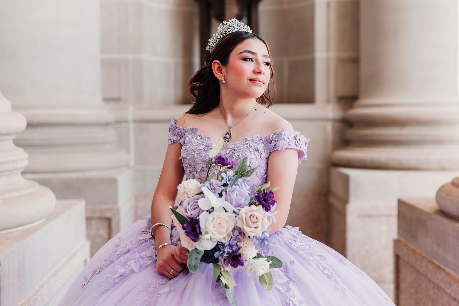 Profile view of a Quinceañera wearing sparkling crystal earrings and an elegant updo hairstyle with cascading curls.