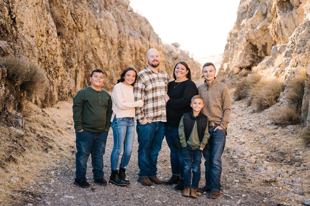 Group portrait in casual attire standing between rocky canyon walls on a desert trail.