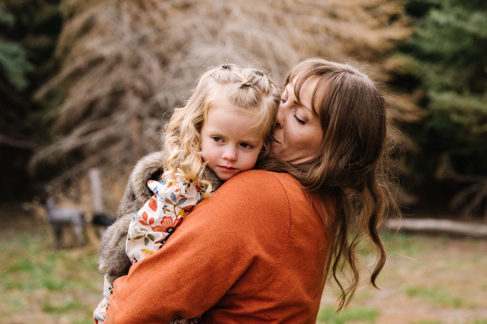 A tender moment between parent and child wearing orange and floral attire outdoors.