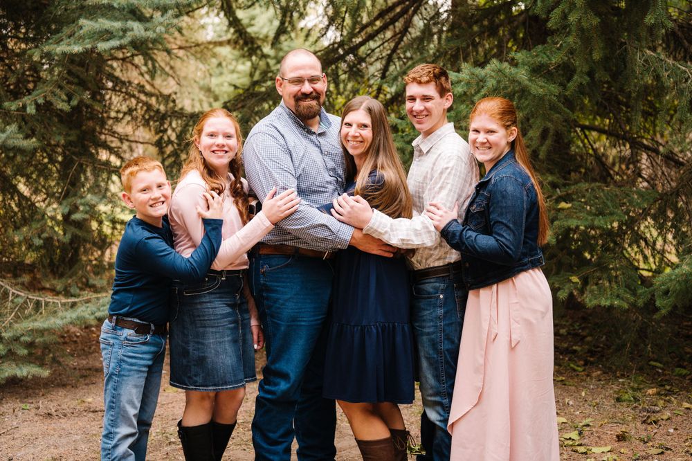A joyful group portrait of a family embracing and laughing together outdoors.