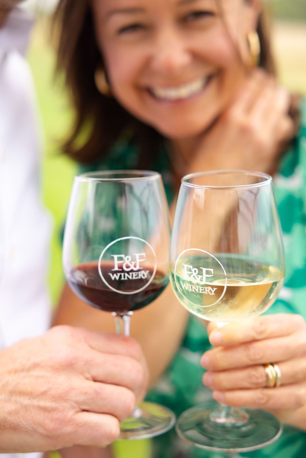 Branding session with wine glasses clink together in a celebratory toast at an outdoor gathering.