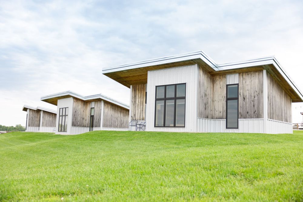 Branding session with panoramic view of contemporary wooden buildings nestled on a green hillside.