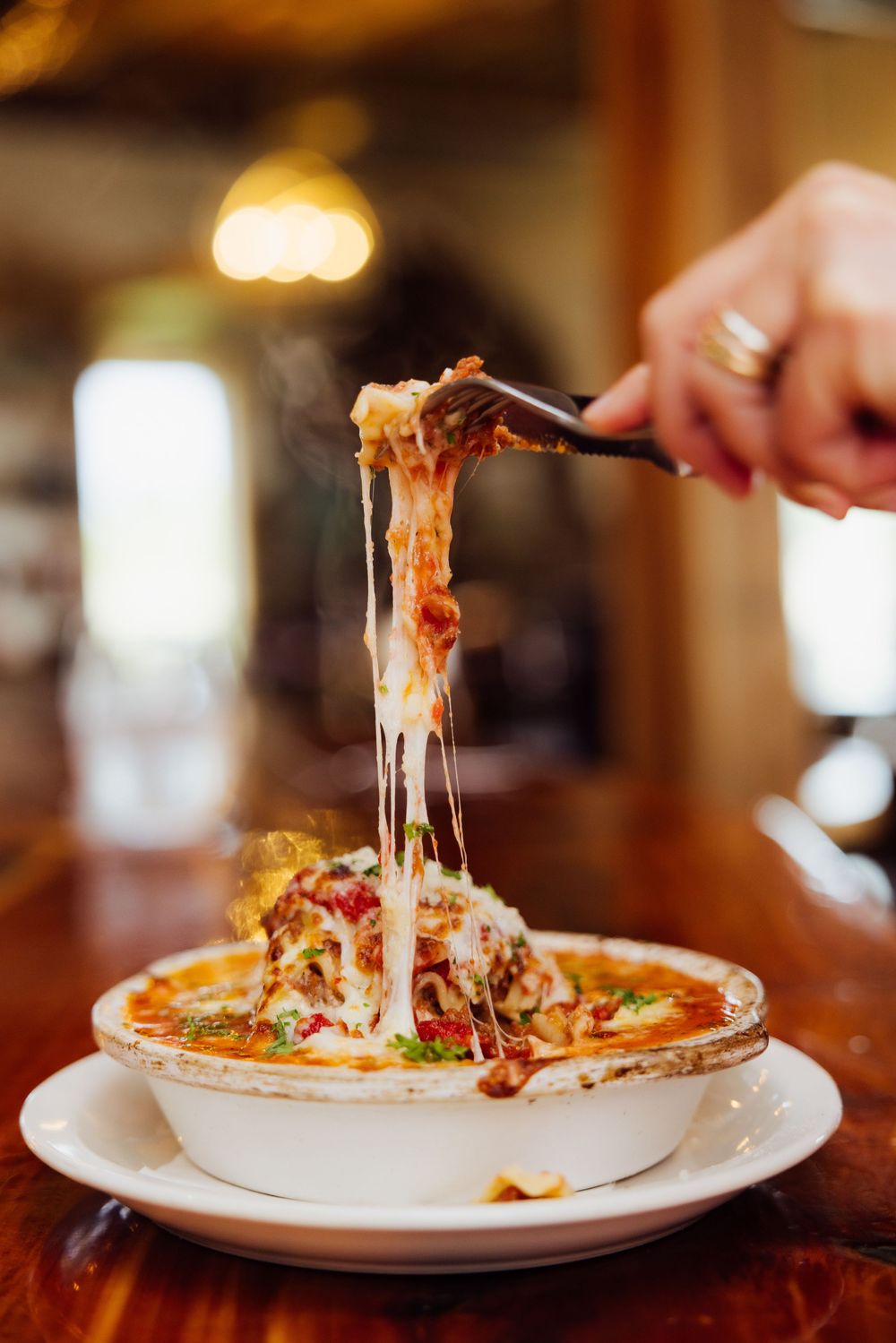 Branding session with stretchy cheese pulls away from a freshly served pizza on a white plate.
