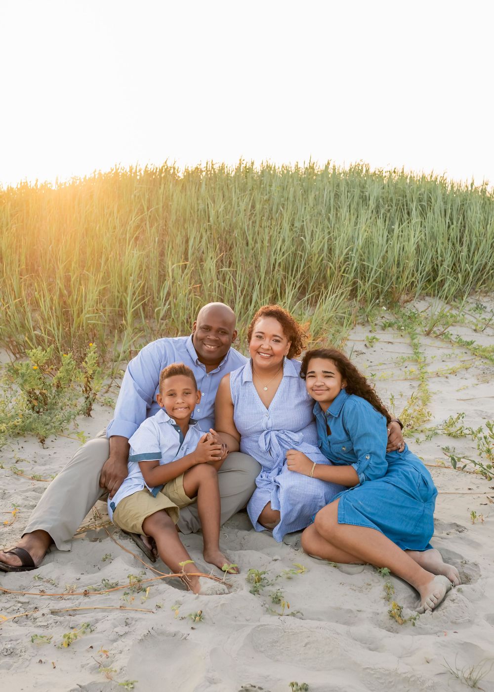 A family relaxes together on a sandy beach dune during golden hour sunset in Galveston, Texas.