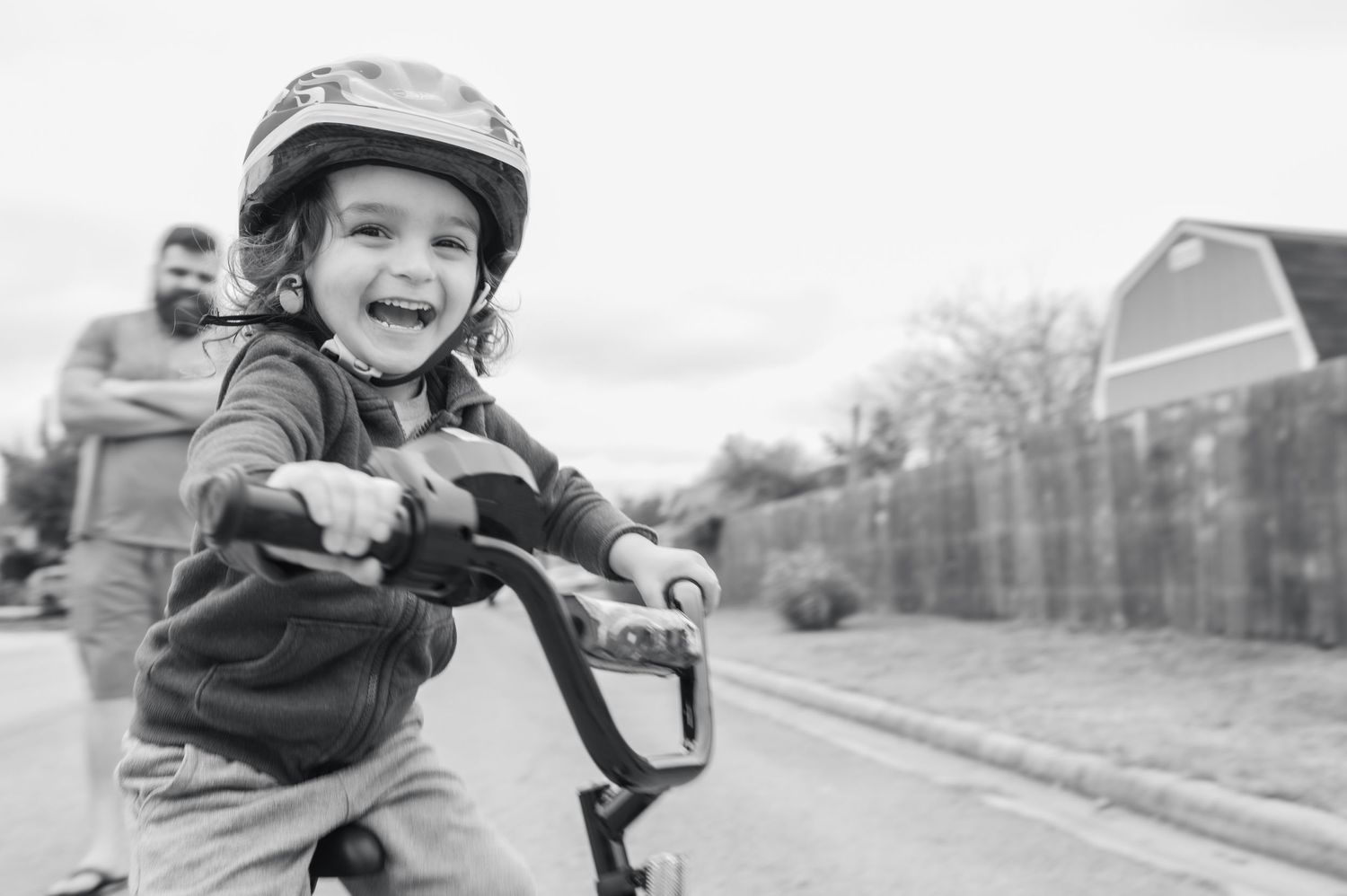 A child wearing a helmet rides a bike with excitement while learning.