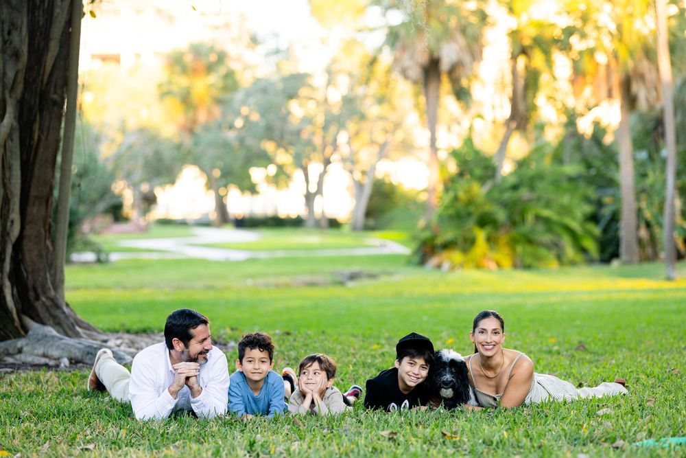 Group of people laying on green grass in a park during golden hour sunset.