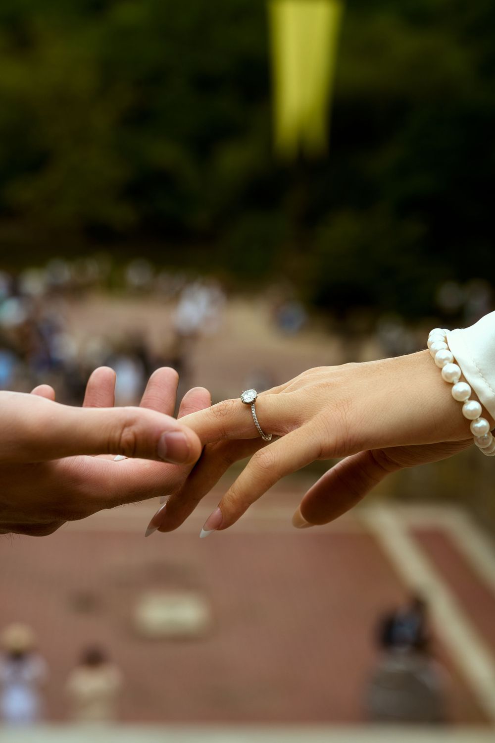 Close-up of hands touching with a pearl bracelet visible against a blurred background.