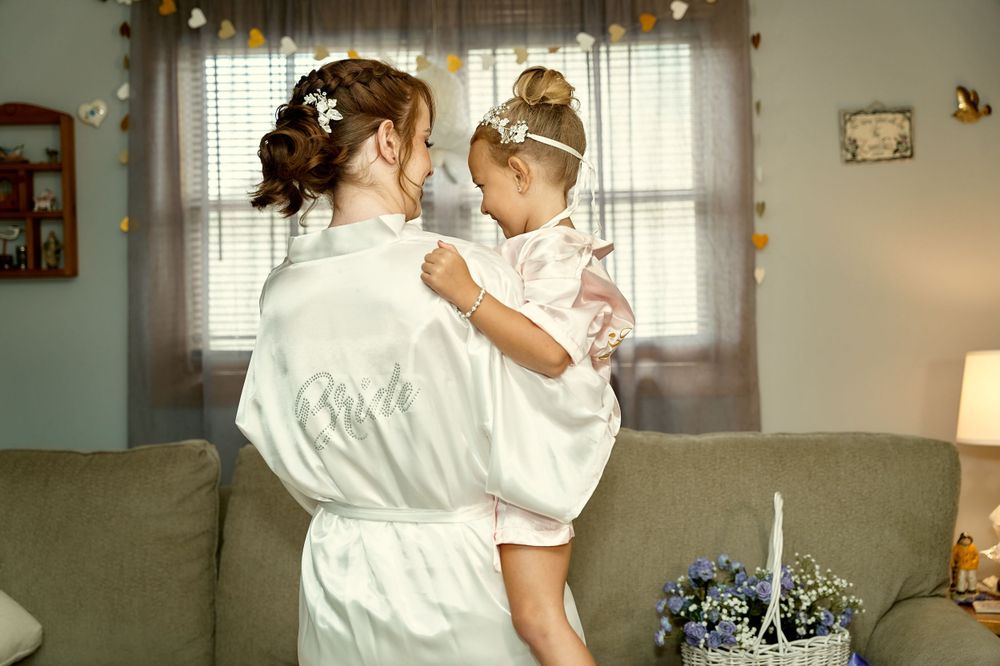 A tender moment between family members dressed in white robes in a cozy living room setting.
