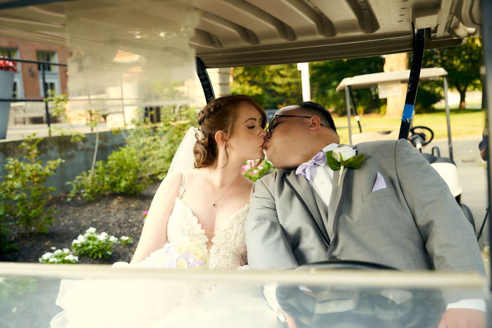 Wedding couple shares intimate moment in decorated vintage car with sunlit background.