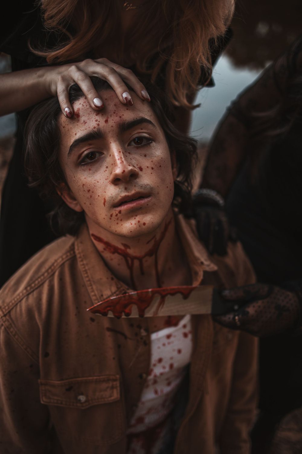 A dramatic horror-themed portrait with stage makeup and blood effects.
