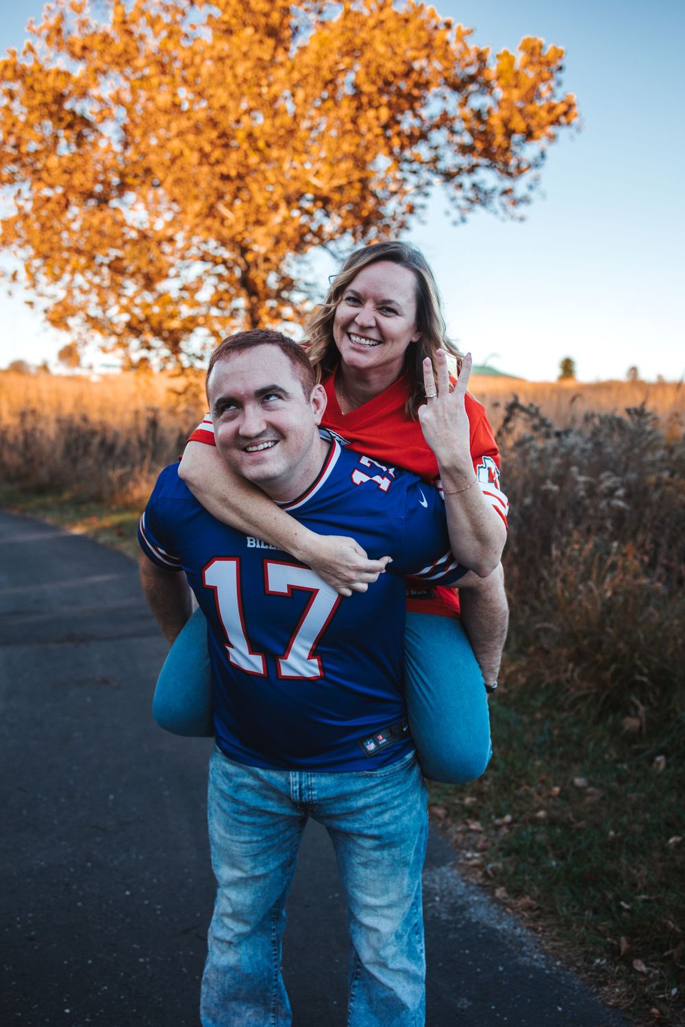 Playful piggyback ride photos captured during golden hour with autumn trees in background.