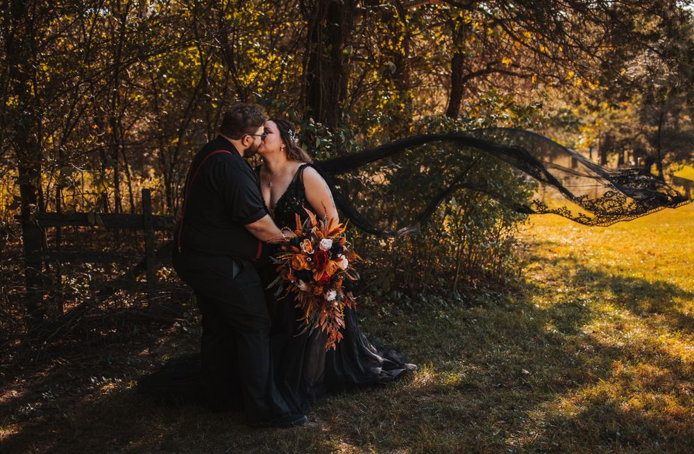 A romantic autumn wedding photo of a couple embracing in golden forest light.