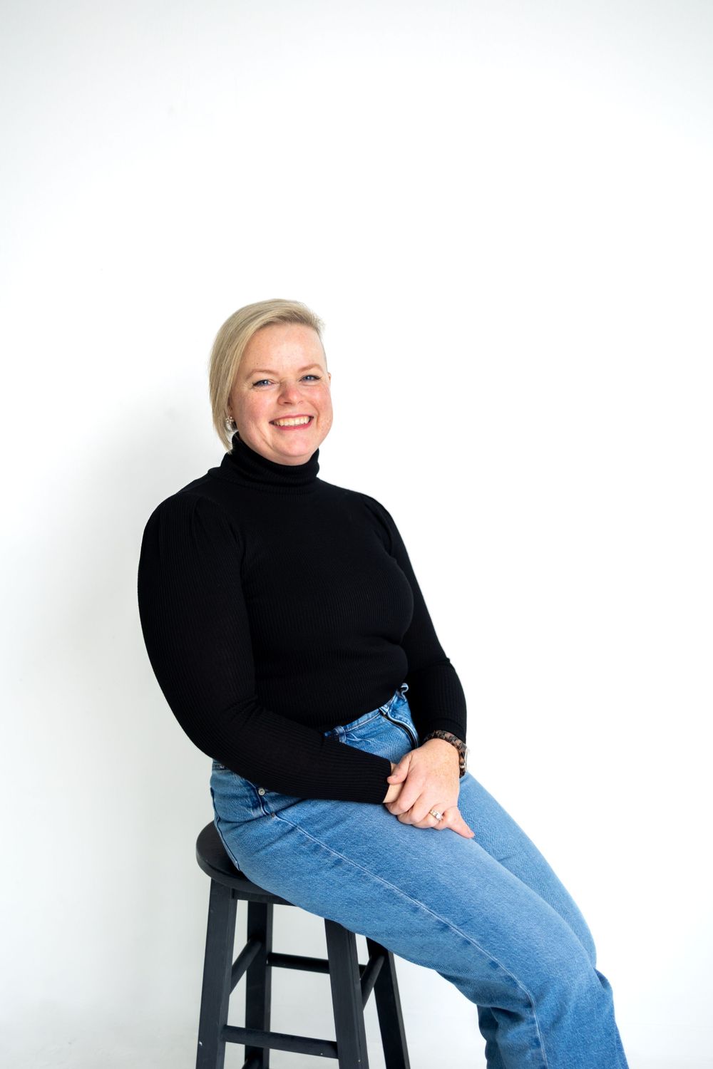 Portrait series showing casual poses on a stool against white background.