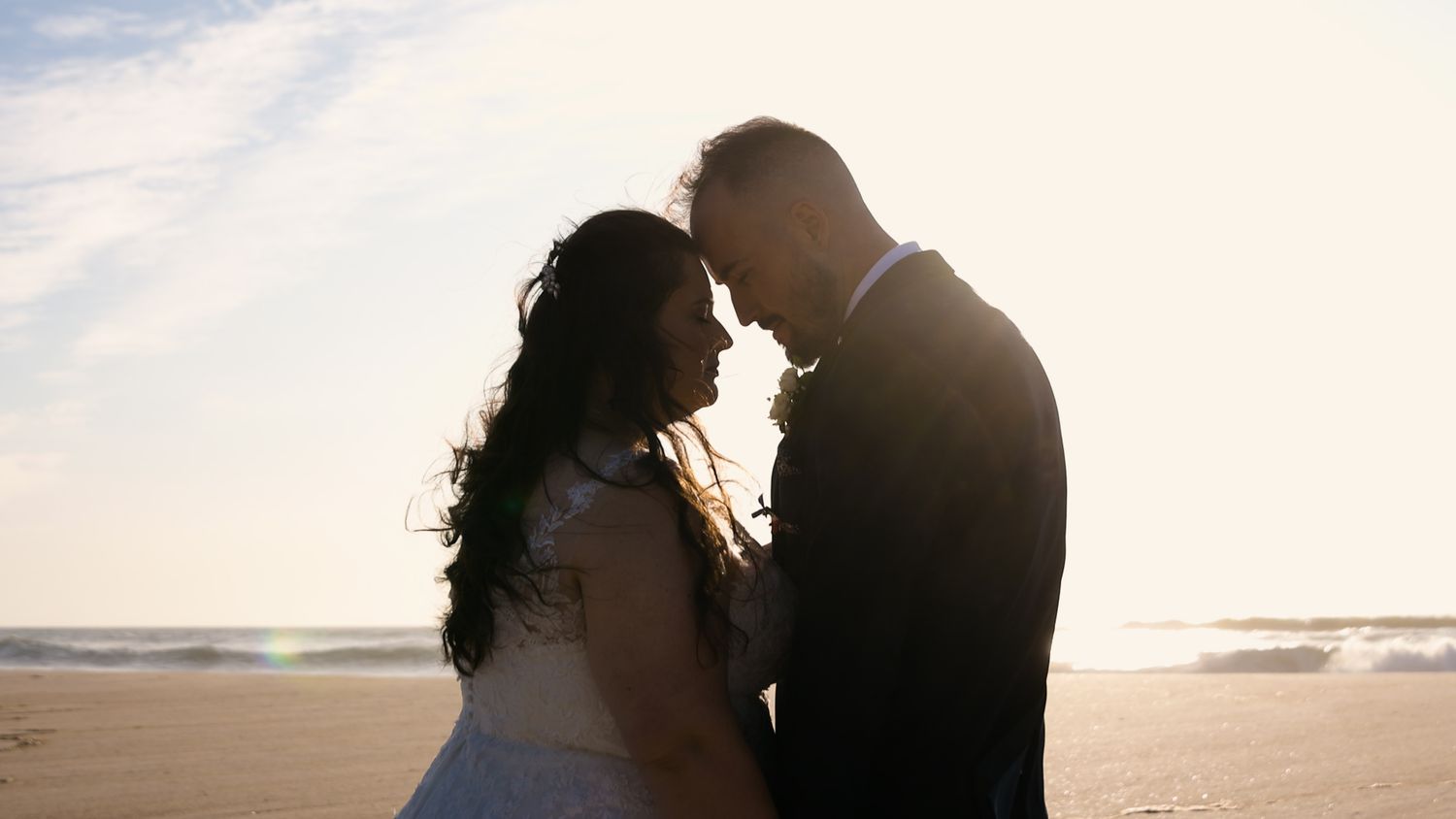 A romantic sunset silhouette of a couple embracing on the beach.