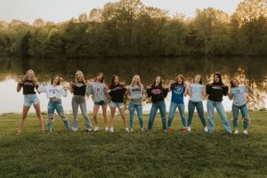 A group of high school senior girls wearing their chosen college apparel. They are proudly showing off where they will be attending school.