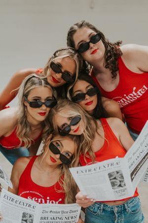 A group of girls wearing black sunglasses and red tank tops. They are posing for the camera with their heads together.