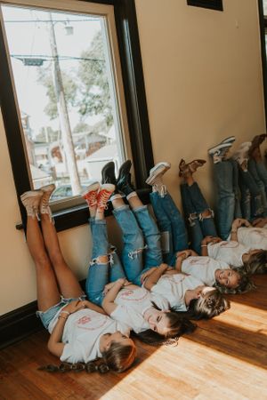 A silly photo of a group of friends laying on the ground with their feet in the air. They are smiling and laughing at each other.