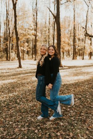 Two best friends at the park in the autumn. They are happy and posing for the photo.